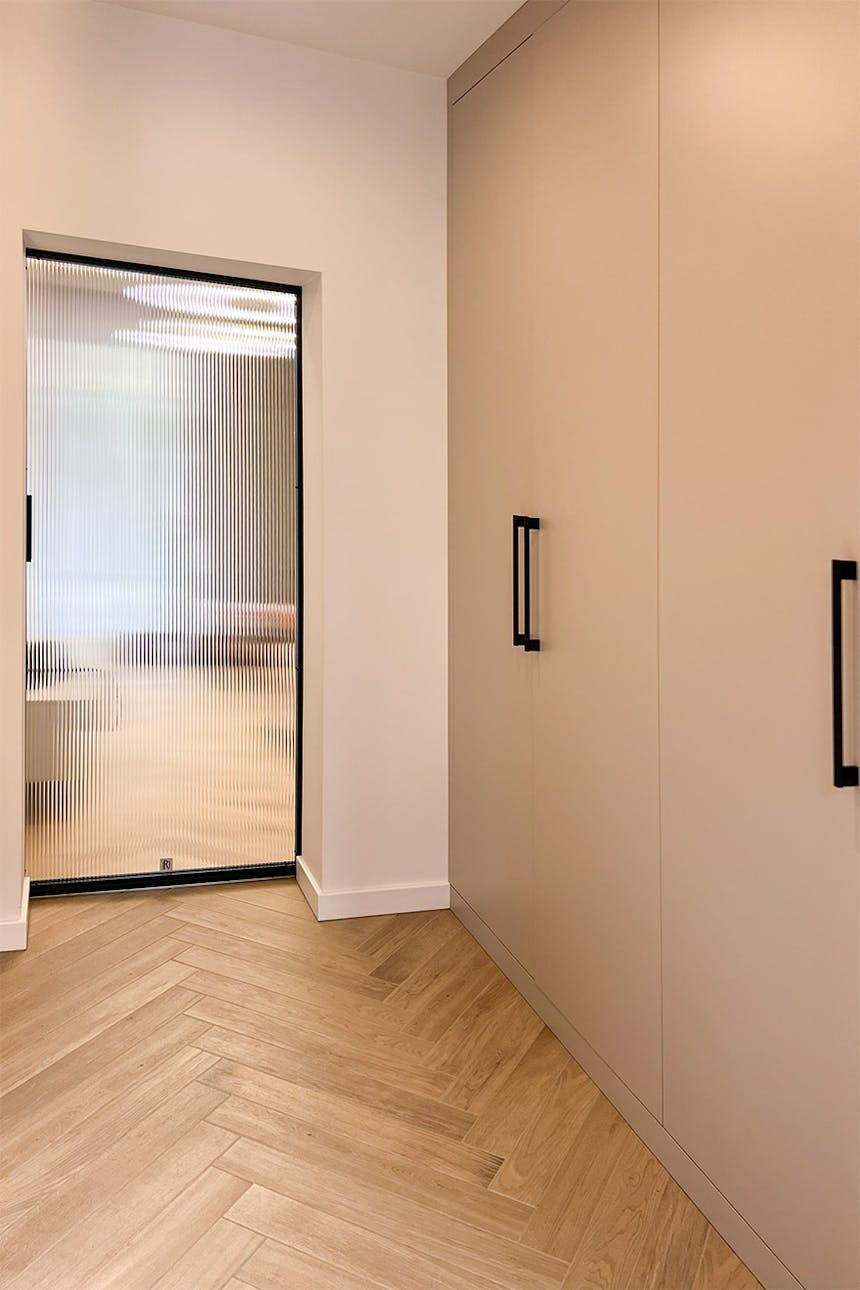 Jasny przedpokój z szafą w kolorze beżowym i szklanymi drzwiami przesuwnymi w stylu minimalistycznym.