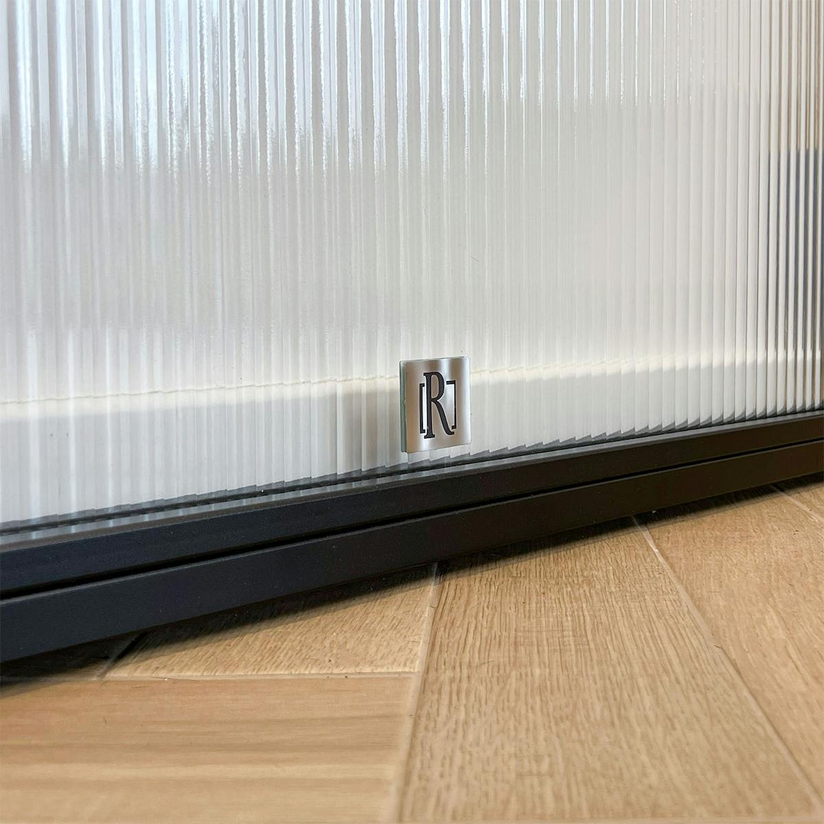 Detal dolnej krawędzi drzwi przesuwnych Reno na tle jasnej podłogi w jodełkę.