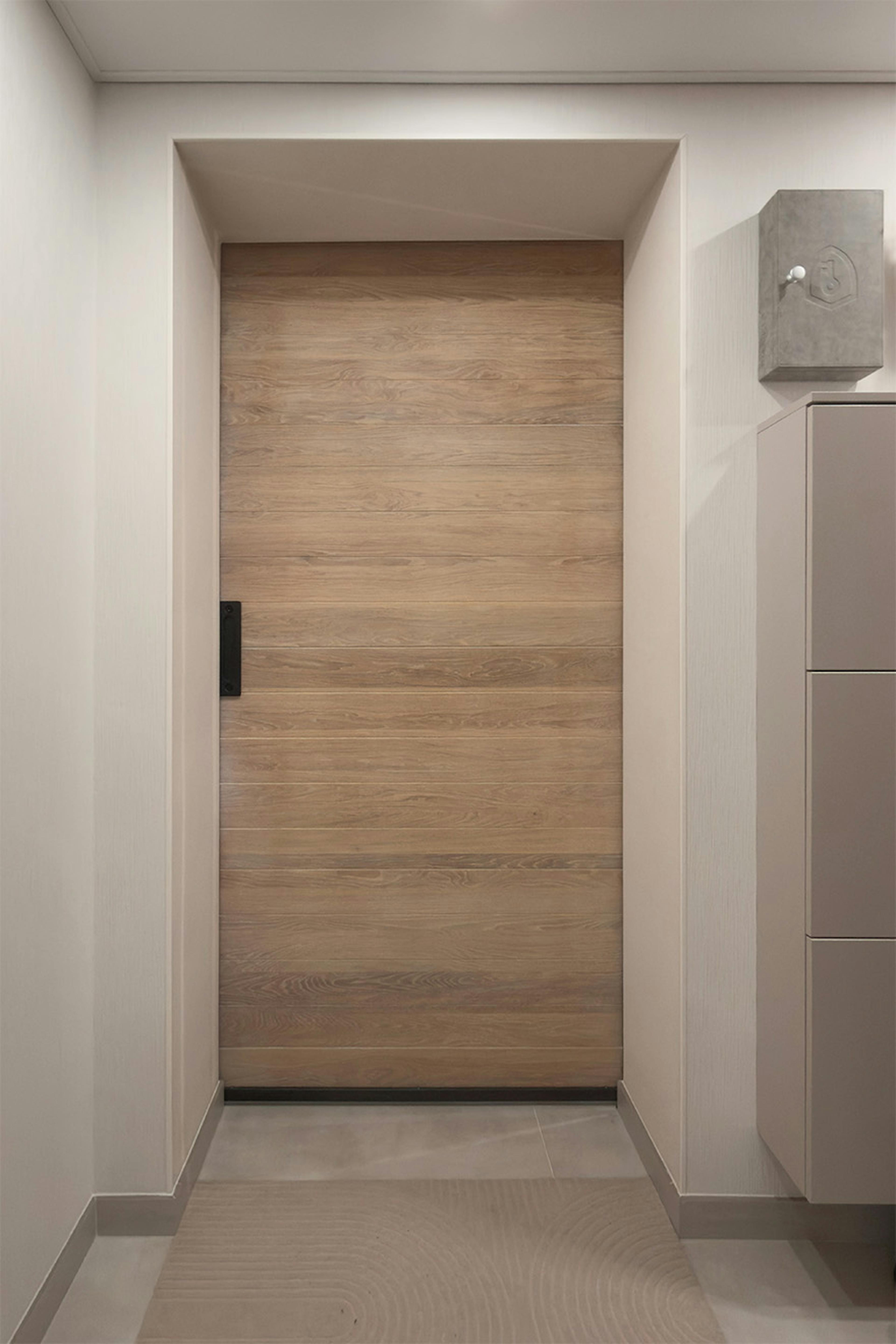 Une porte coulissante en chêne blanchi installée dans l'embrasure d'un couloir moderne.