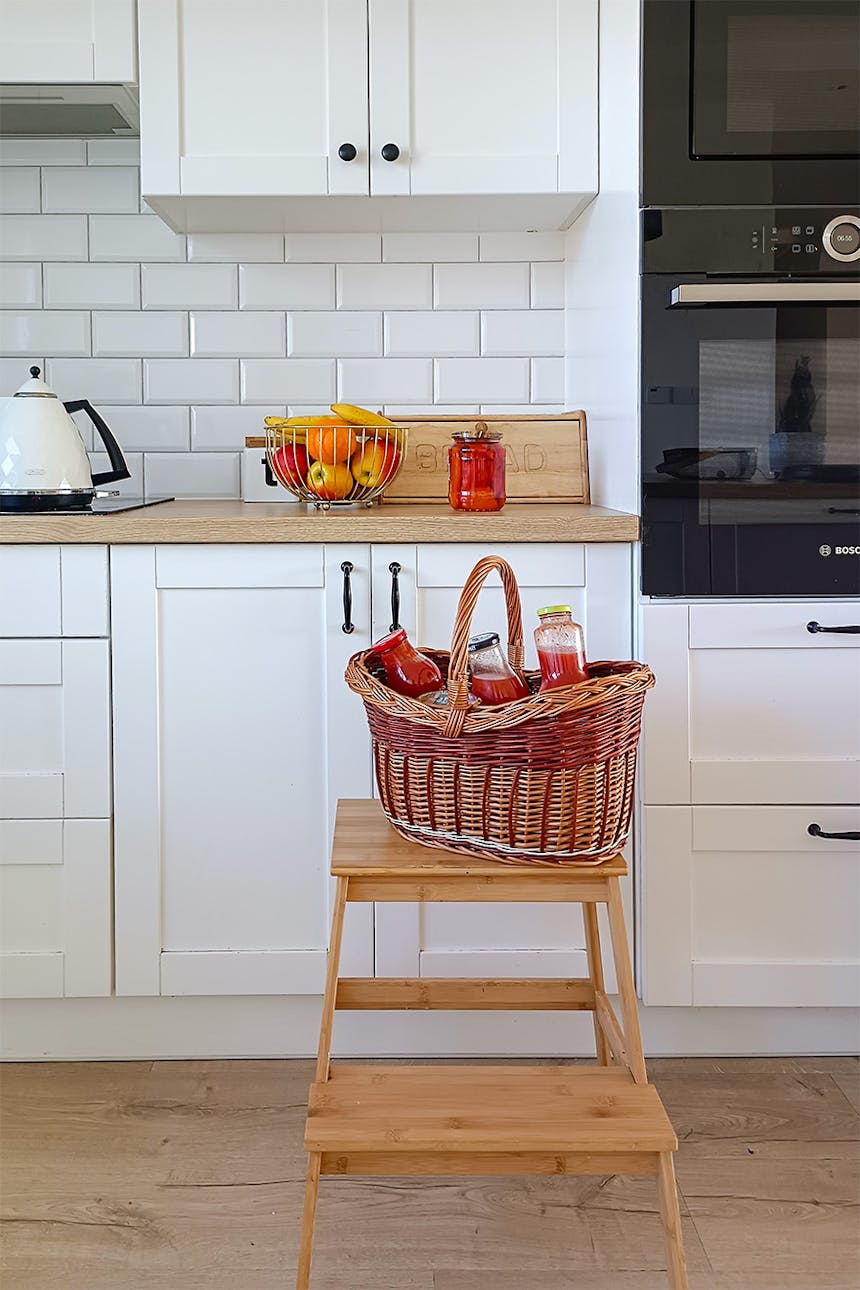 drewniana podłoga, białe meble i białe płytki w kuchni