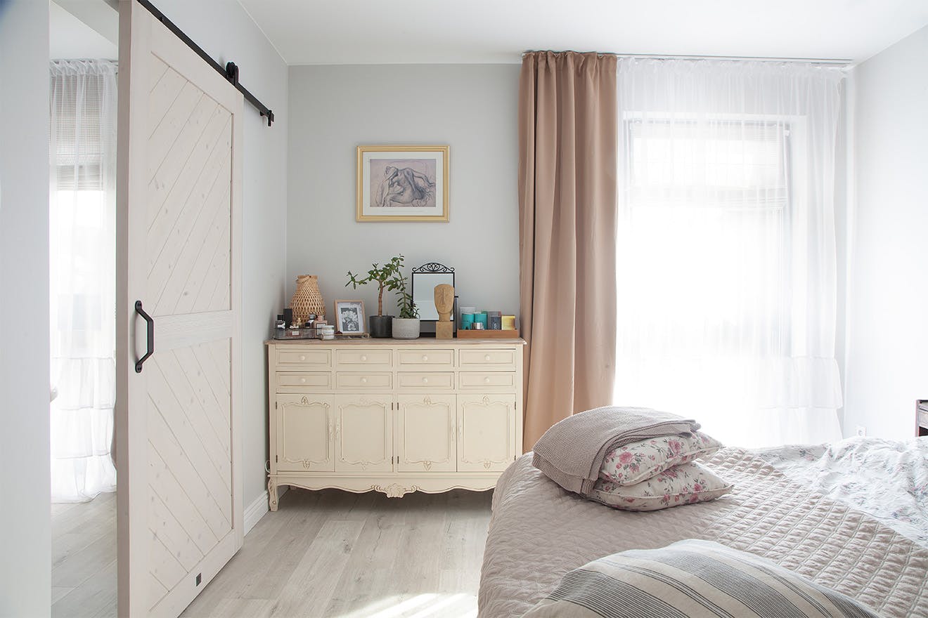 a bright and spacious bedroom with a bathroom hidden behind white sliding doors