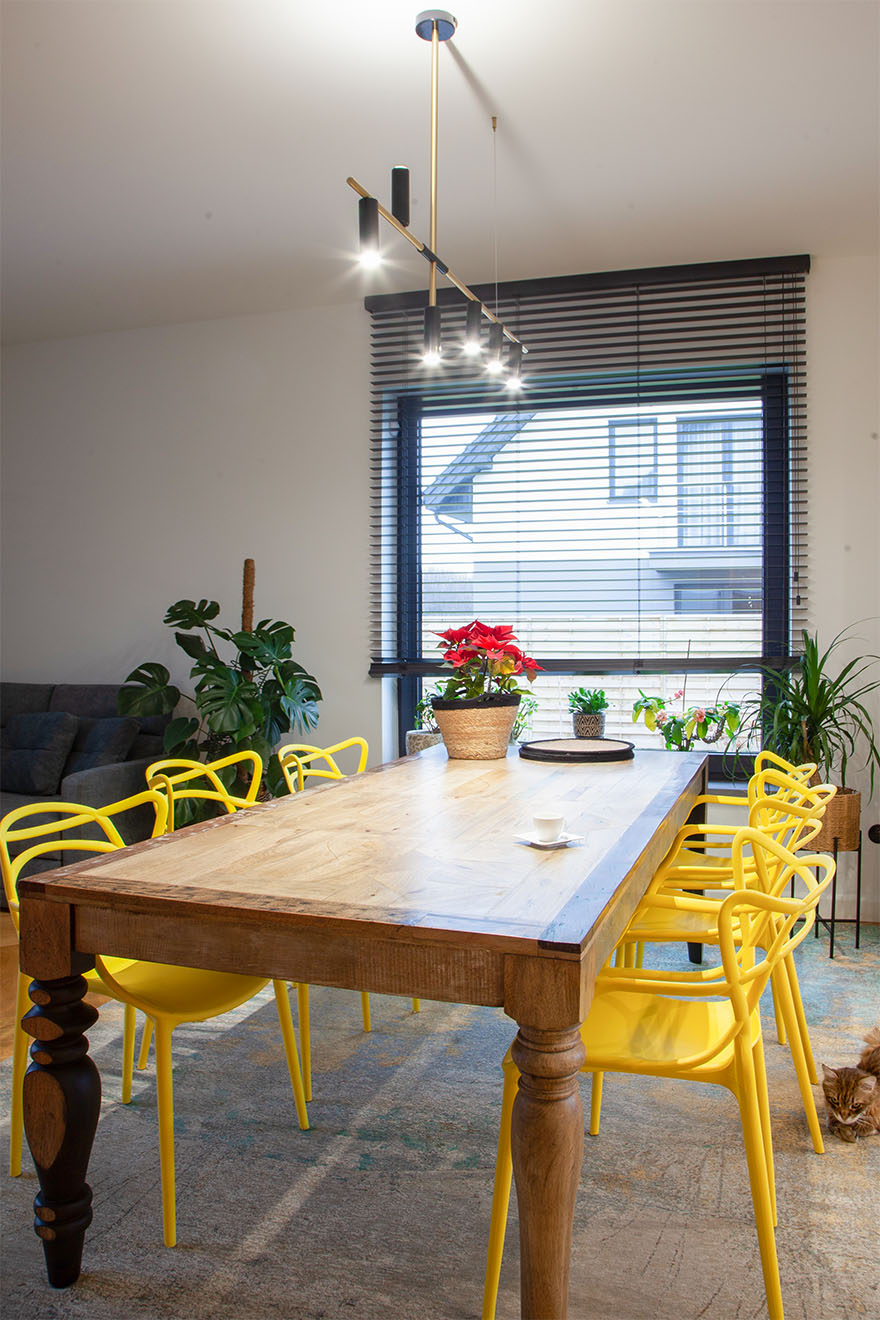 großer Holztisch und gelbe Stühle in einem modernen Speisesaal