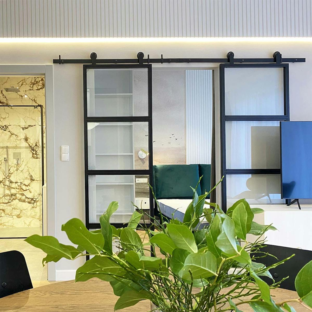 podwójne, szklane drzwi przesuwne oddzielające salon od sypialni w nowoczesnym mieszkaniu