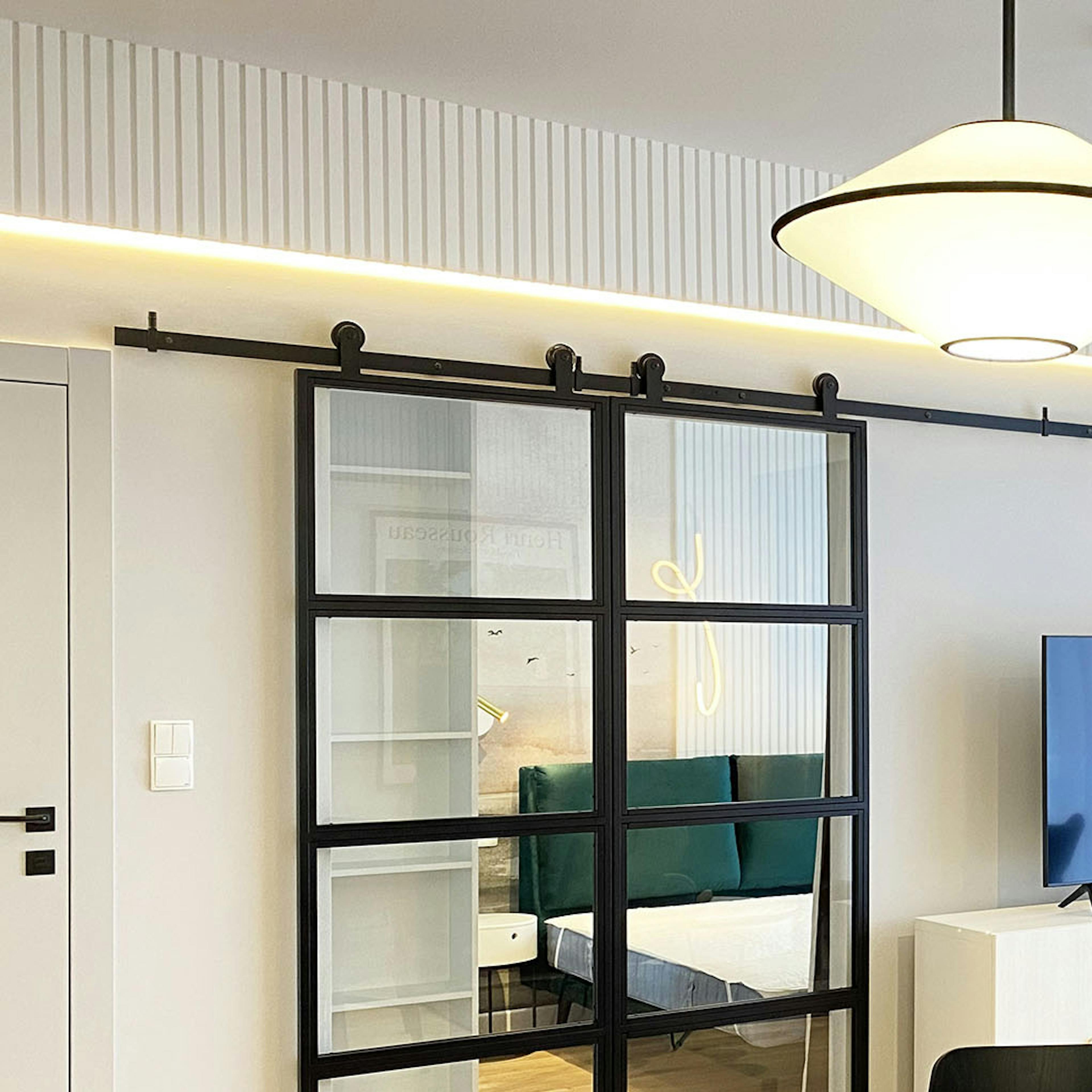 portes coulissantes en double vitrage dans un cadre métallique séparant le salon de la chambre dans un appartement moderne