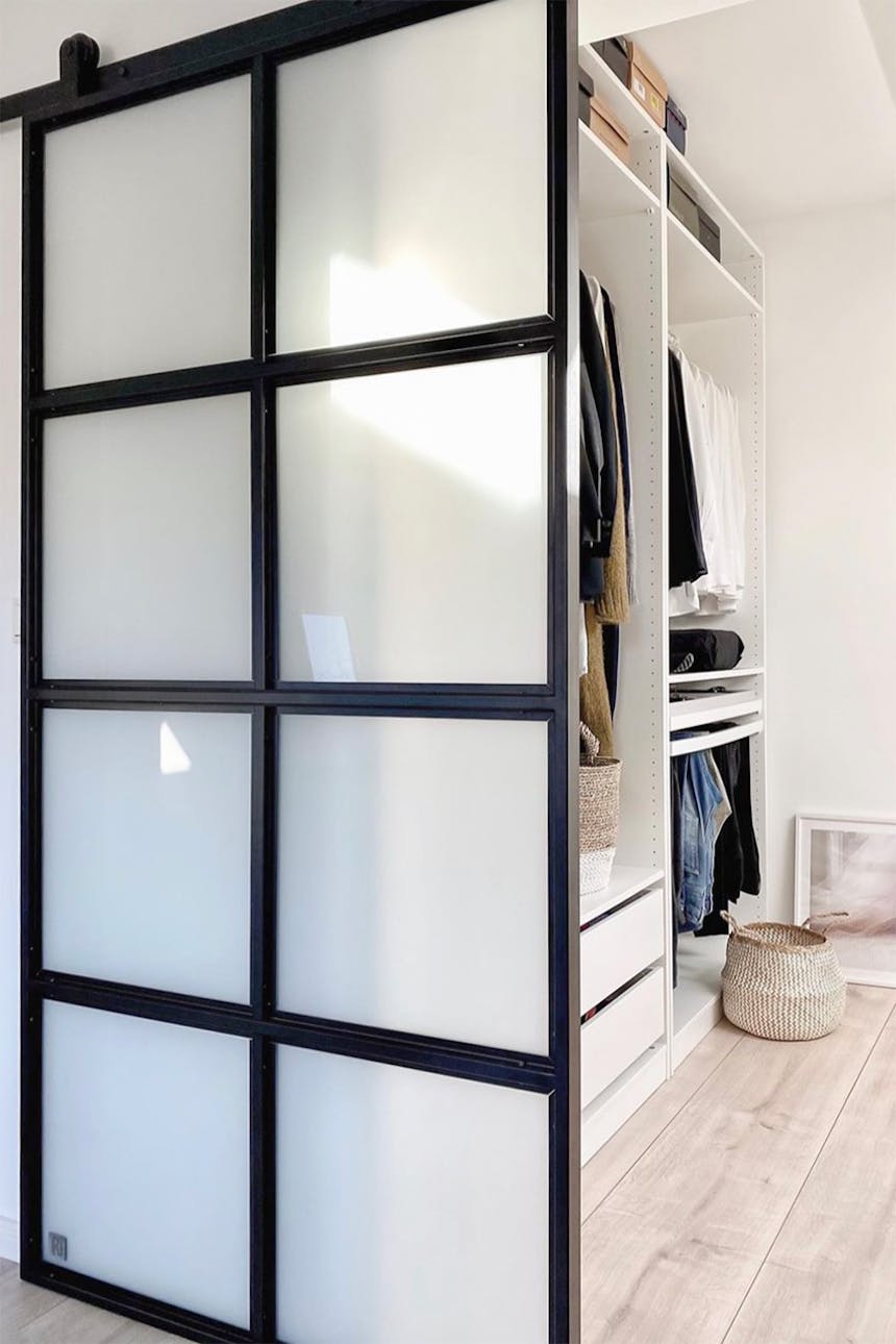 Loft-Schiebetüren mit Glas zu einem Ankleidezimmer mit weißen Möbeln