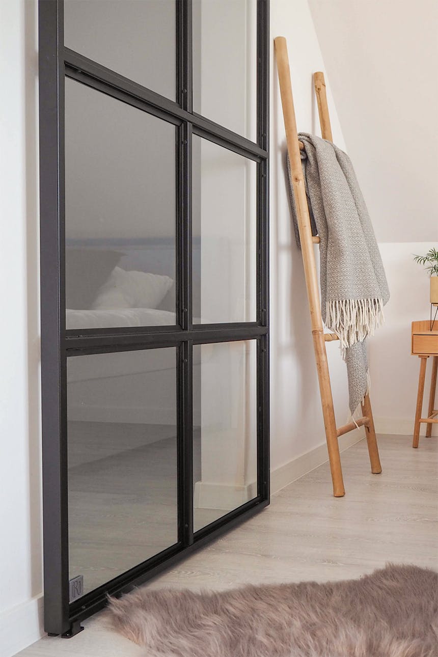 Glasschiebetüren in einem schwarzen Metallrahmen im Eingang zur Dachbodengarderobe