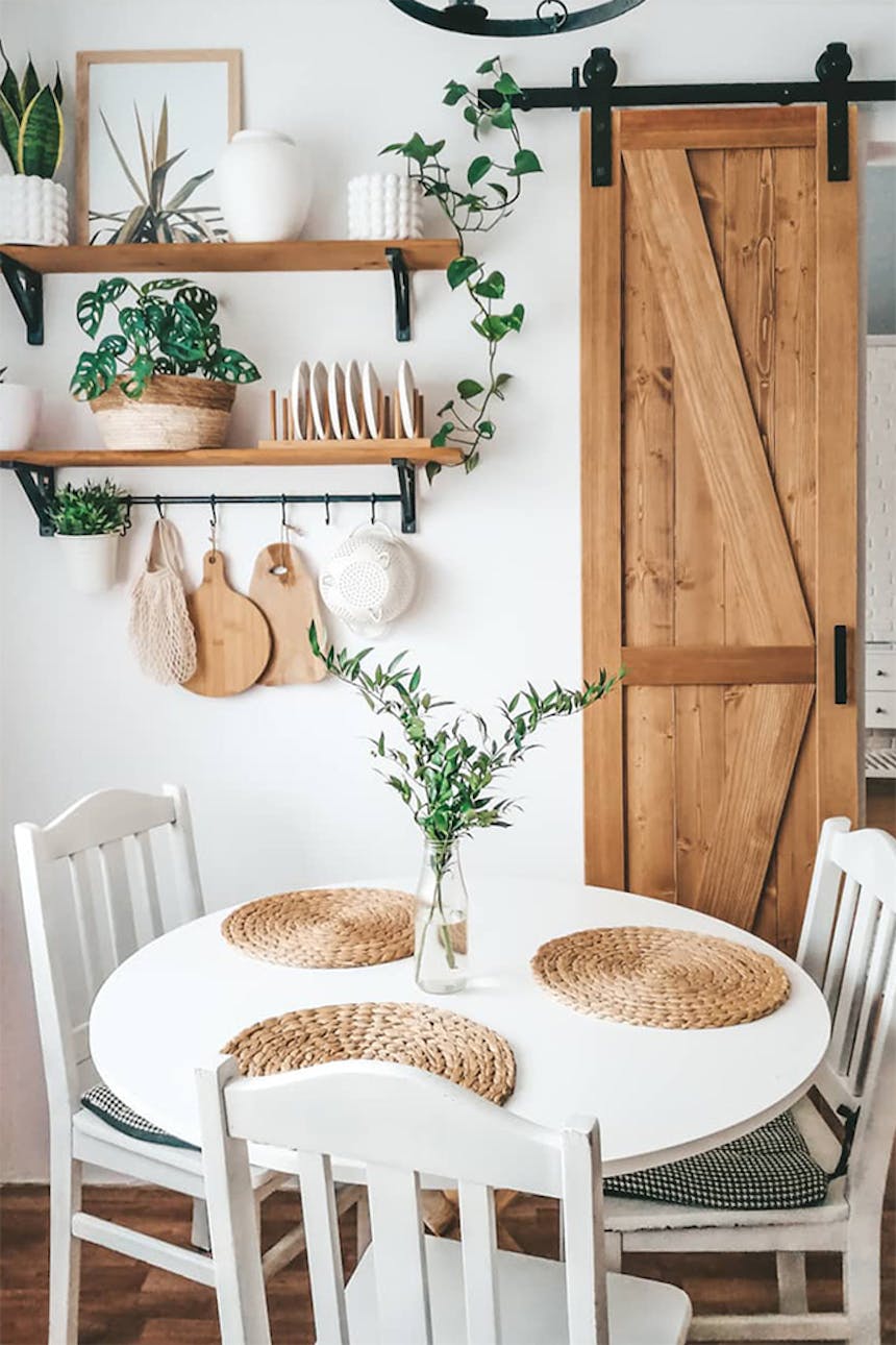 Holzregal für Küchenzubehör, schmale Holzschiebetür, Dekorationen im Boho-Stil, weißer runder Tisch in der Küche, weißer Tisch und weiße Stühle, Holzaccessoires in der Küche