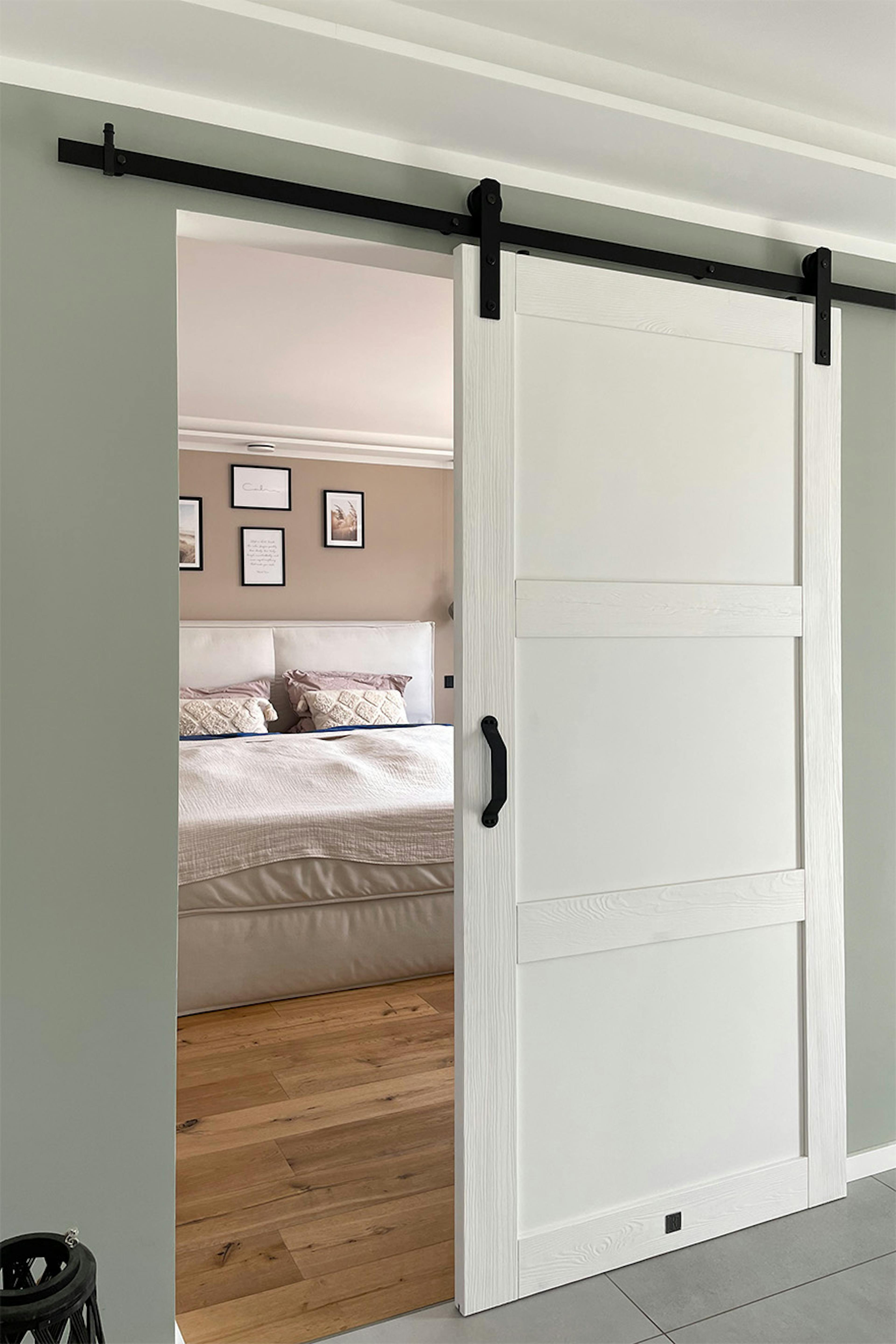porte coulissante blanche à la chambre à coucher, porte blanche sur le système coulissant noir, entrée à la chambre à coucher moderne
