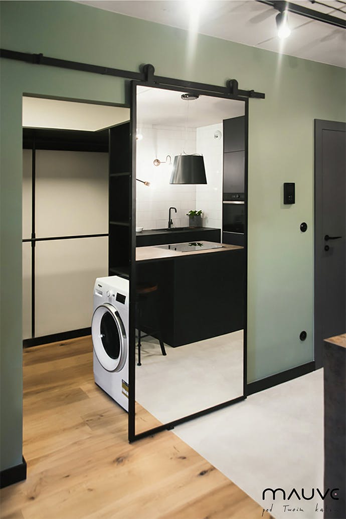 Porte coulissante industrielle avec miroir dans l'entrée de la salle de bain dans un petit appartement