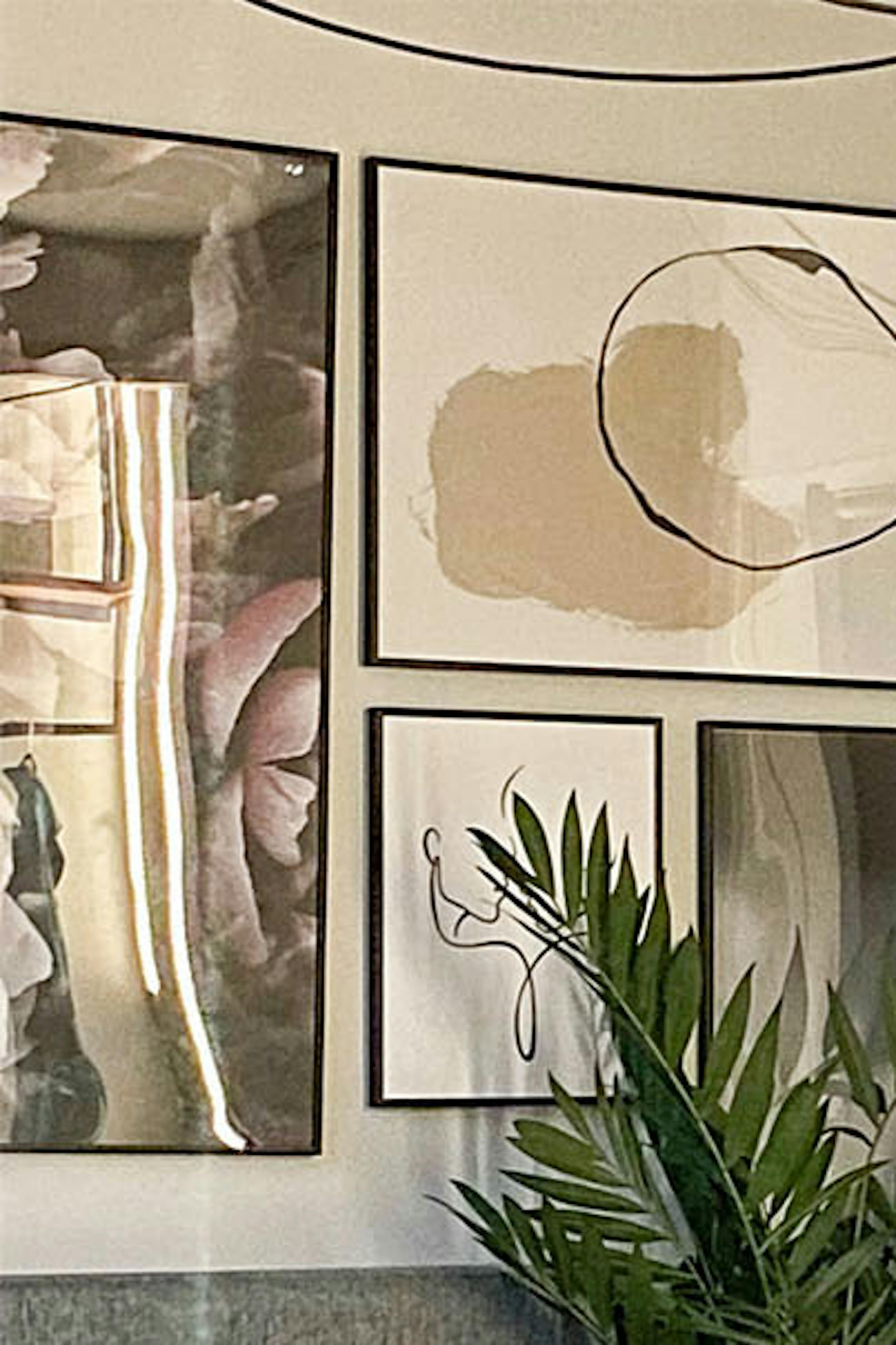 un coin dans la chambre à côté d'un lit capitonné gris, avec une petite coiffeuse et une galerie d'affiches murales