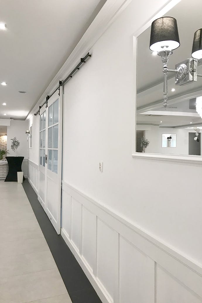 un miroir dans un cadre blanc et une porte coulissante blanche avec du verre sur un mur blanc dans la salle de bal