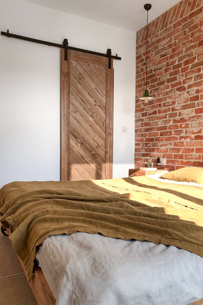 porte coulissante en bois, brique au mur dans la chambre, porte coulissante vers l'armoire, chambre avec dressing, chambre style loft, suspension en métal pour la chambre
