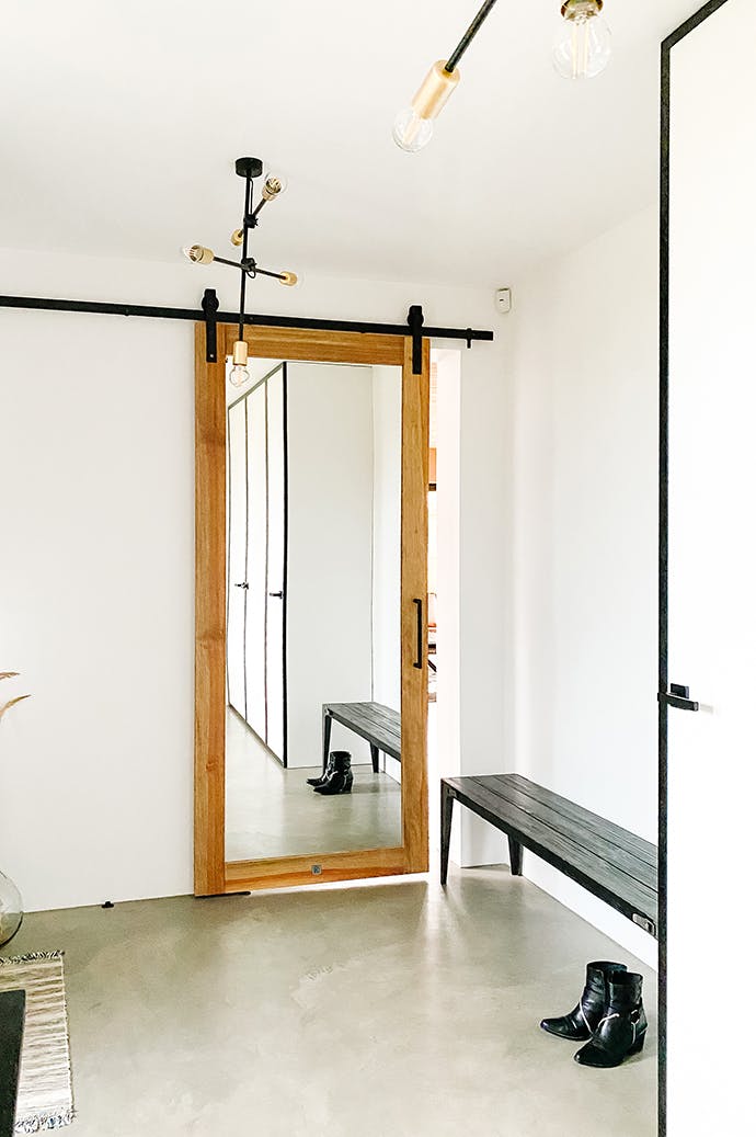 Un vestibule au style minimaliste avec un grand miroir coulissant et une lampe industrielle