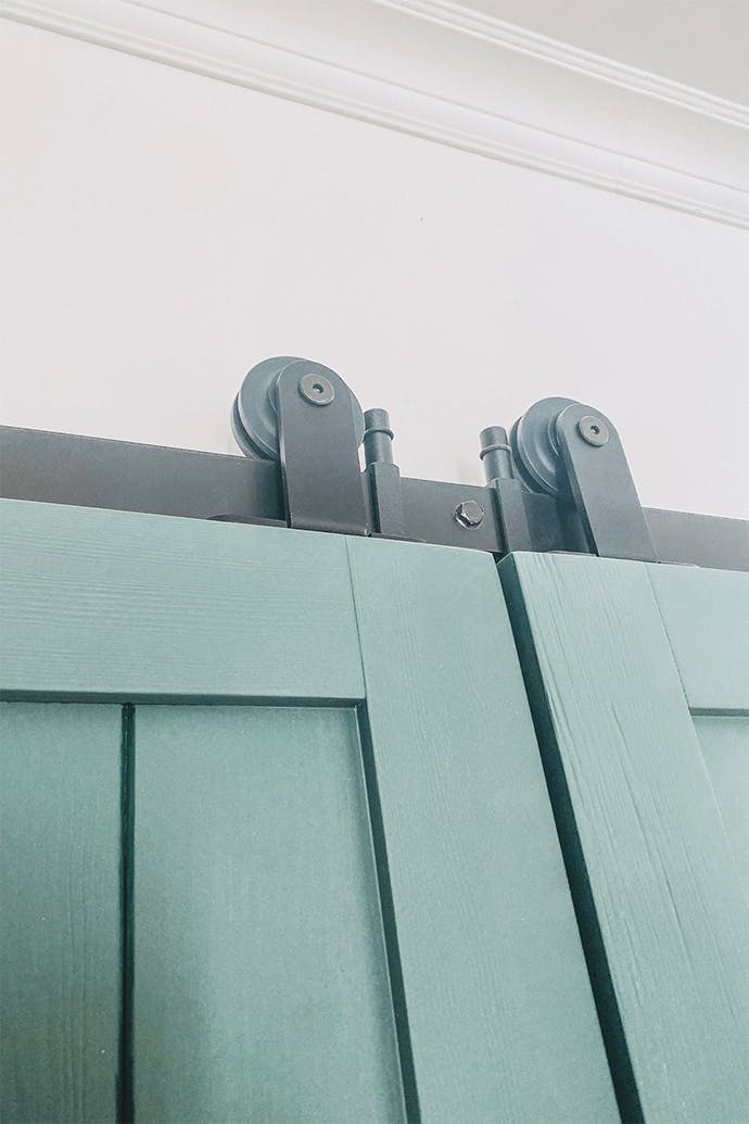 porte en bois verte avec système coulissant noir installé