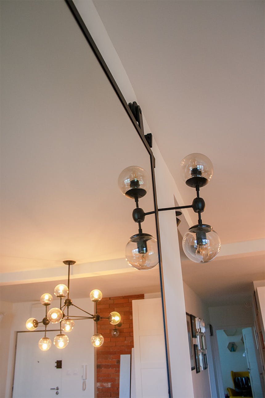 Schiebetür mit Spiegel, Tür mit Spiegel in einem Metallrahmen, Schiebetür in einem modernen Innenraum, hängende Glaslampen aus Metall