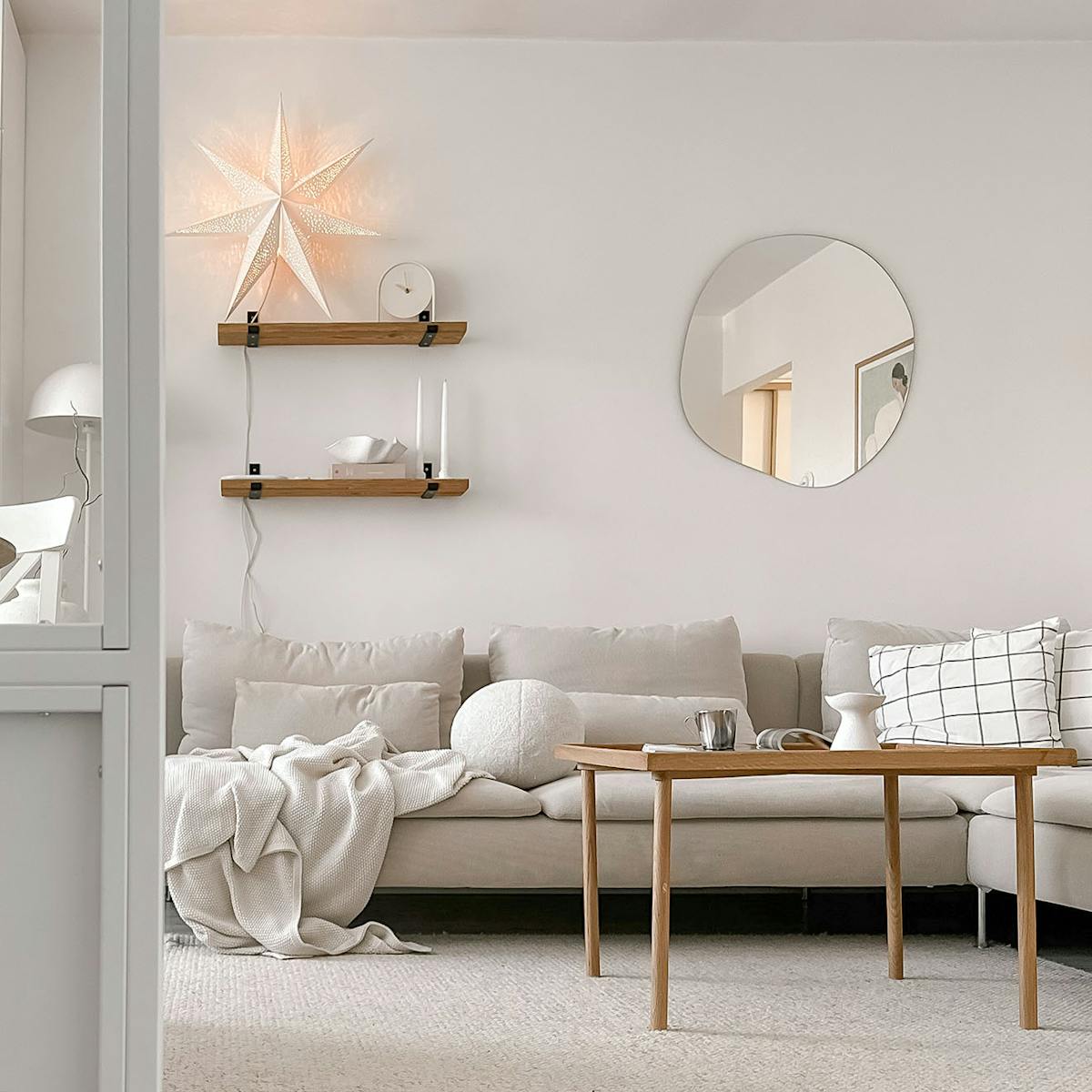 sofa w neutralnym odcieniu, drewniany stolik kawowy w jasnym salonie w bloku