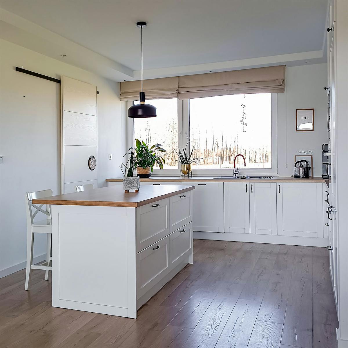 duża wyspa w białej kuchni ze spiżarnią