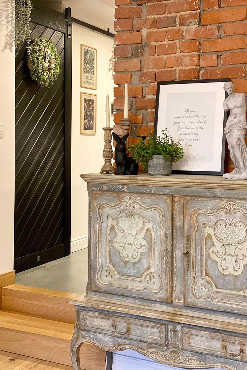 antike kommode im rustikalen stil, roter backstein an der wand im wohnzimmer, schwarze schiebetüren