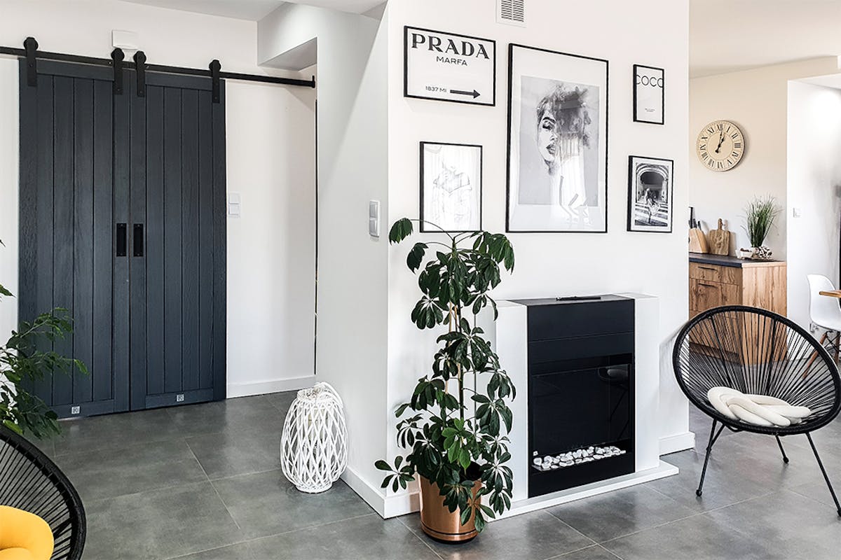 vestibule d'une maison moderne avec doubles portes coulissantes, galerie d'affiches au mur et chaises ajourées