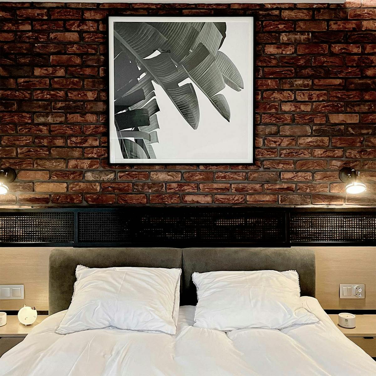 gerahmtes Schwarz-Weiß-Poster an einer roten Backsteinmauer, rote Backsteine an einer Wand in einem industriellen Schlafzimmer, industrielle Dekorationen in einem Schlafzimmer