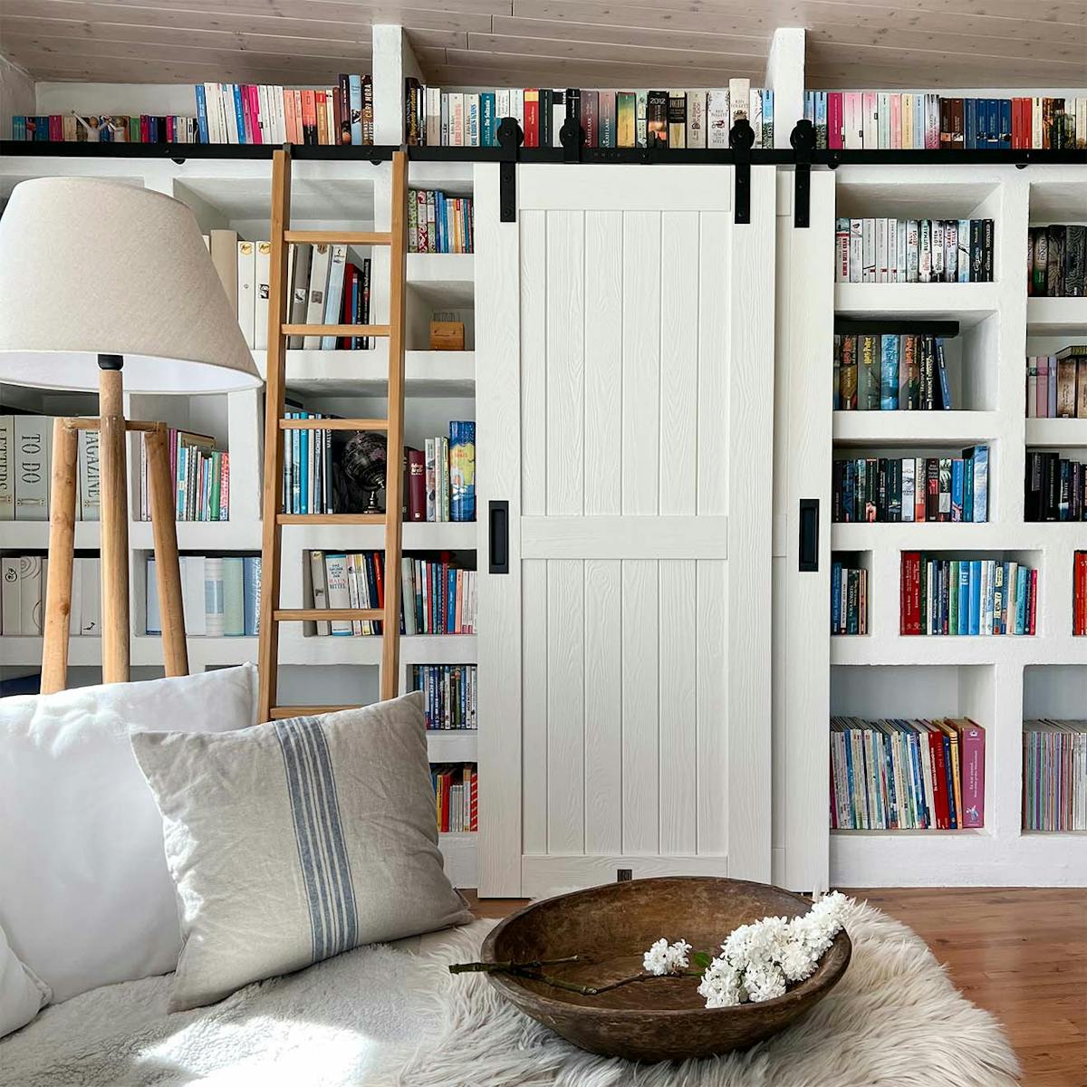 Doppelte weiße Türen und Leiter an der Wand mit Büchern in der Wohnzimmerbibliothek