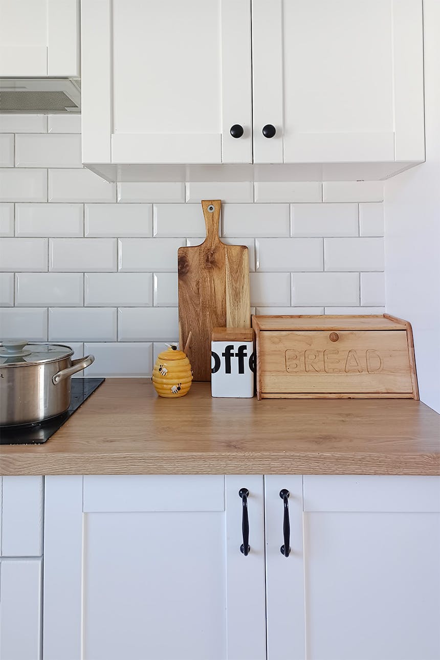 weiße möbel, weiße fliesen, holzarbeitsplatte in einer modernen küche