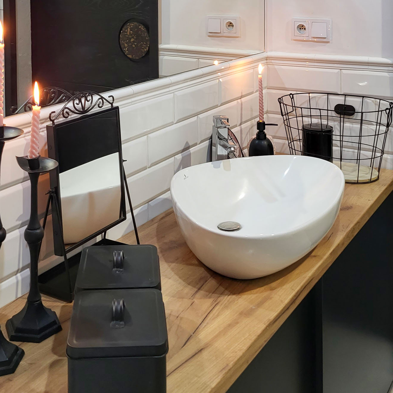 schwarze Accessoires und ein weißes Waschbecken auf einer Holzablage im Badezimmer