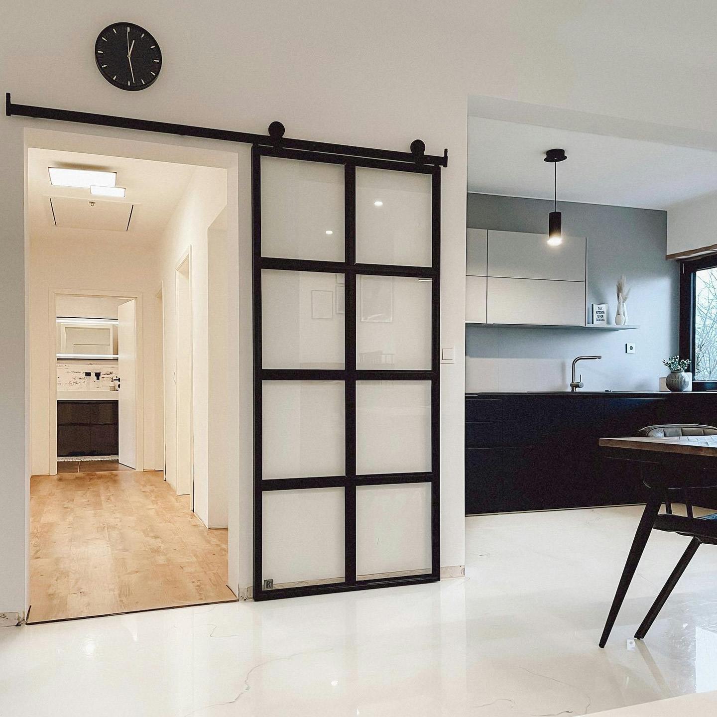 sliding glass doors, metal door with transparent glass, black and white open plan kitchen, black clock on white wall