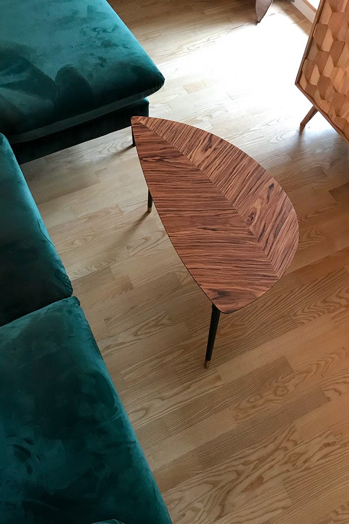 une petite table basse à côté du canapé émeraude