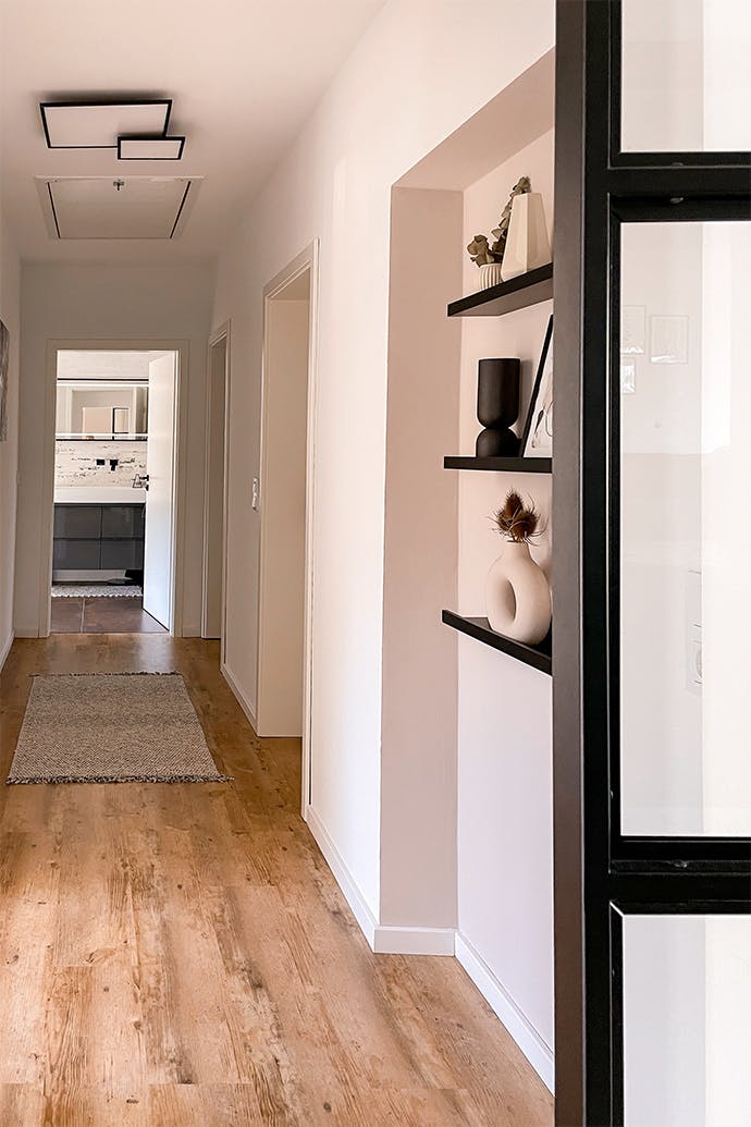 Un couloir au design minimaliste avec de petites décorations et des accessoires noirs