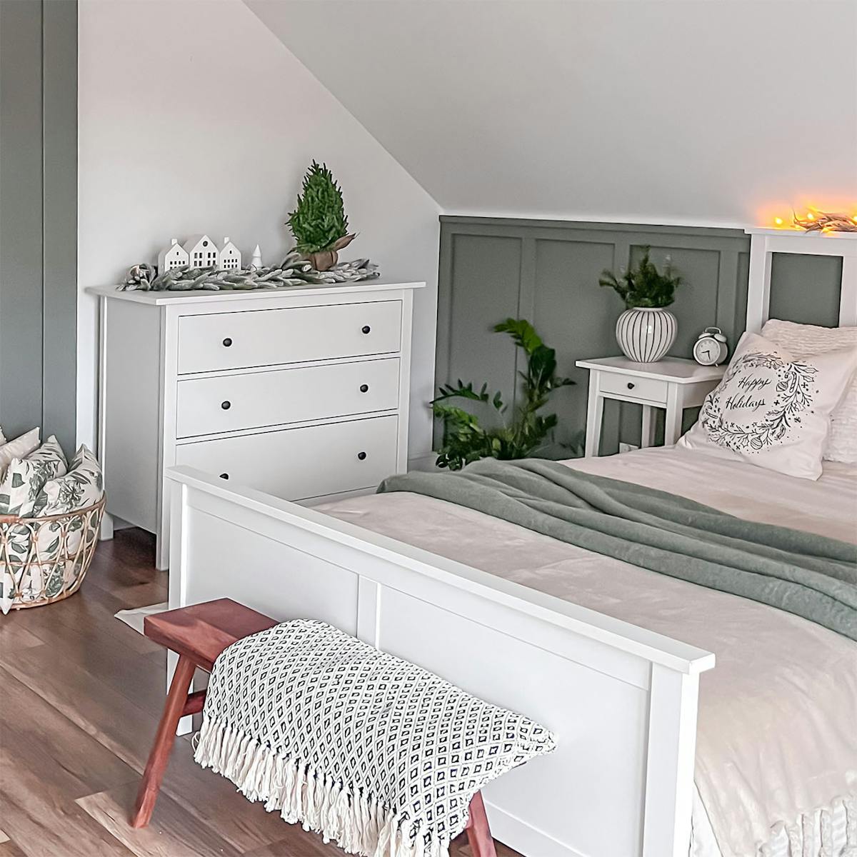 ein weißes Bett und eine weiße Kommode unter einer schrägen Decke im Schlafzimmer