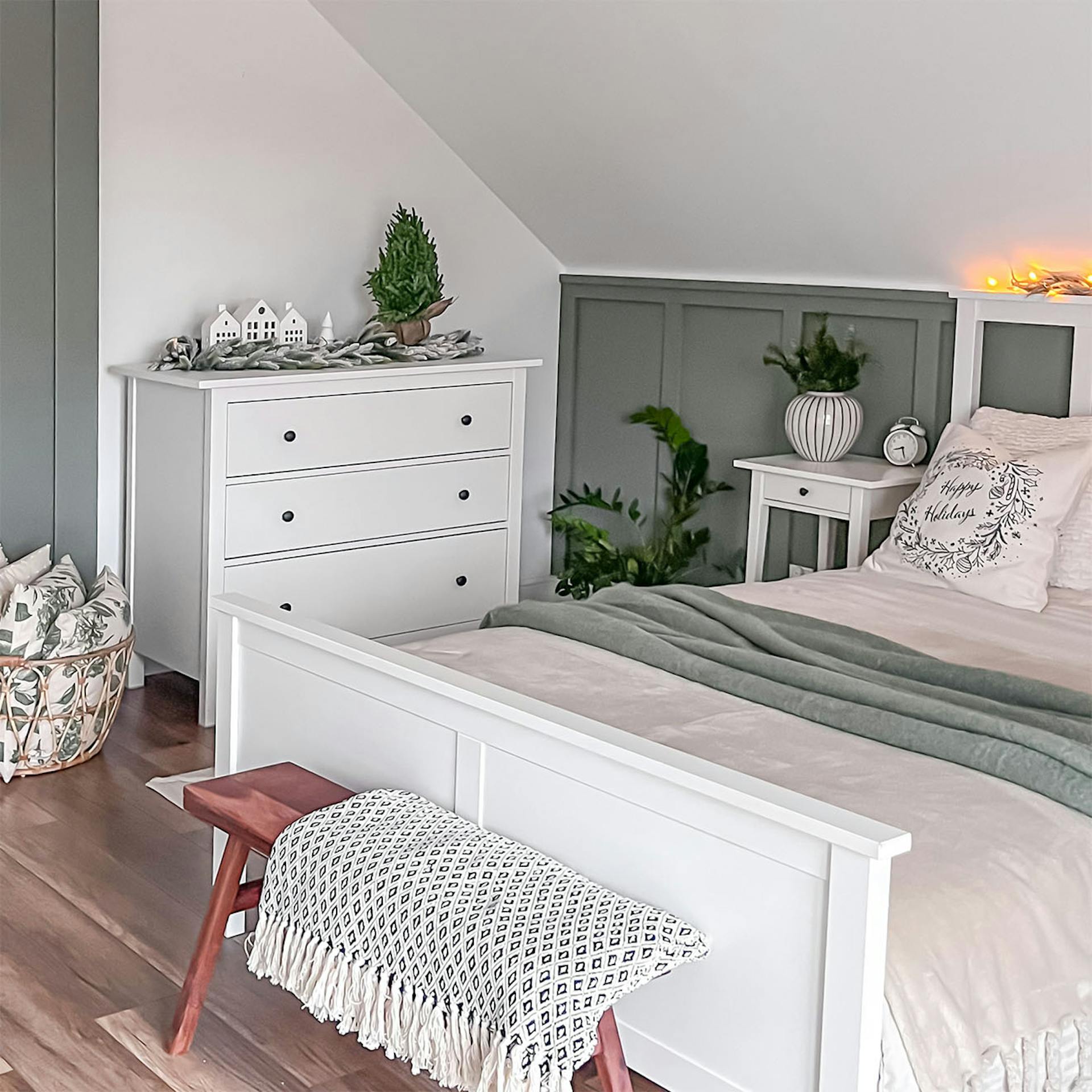 ein weißes Bett und eine weiße Kommode unter einer schrägen Decke im Schlafzimmer