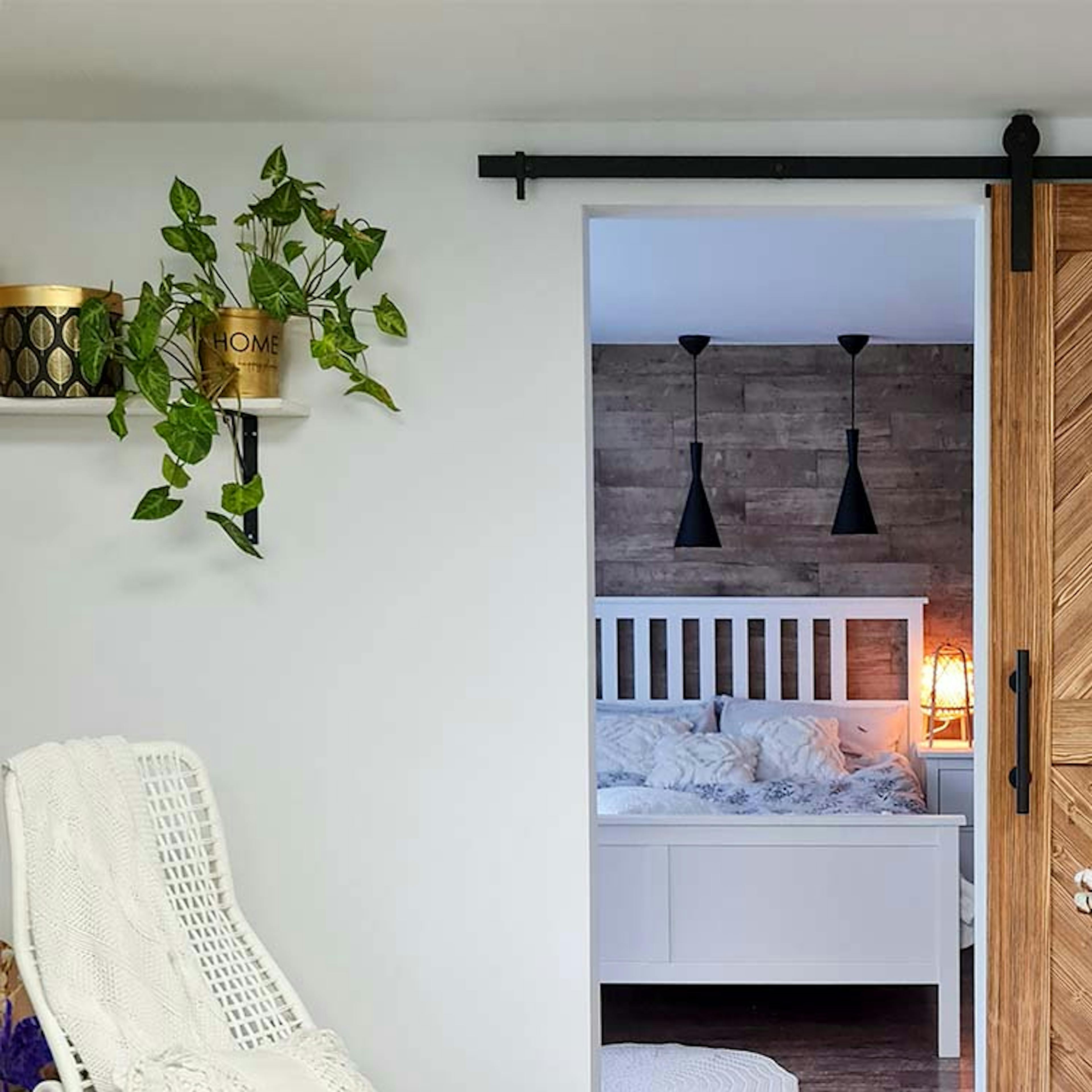 une chaise berçante blanche devant une porte coulissante menant à une chambre avec un lit blanc