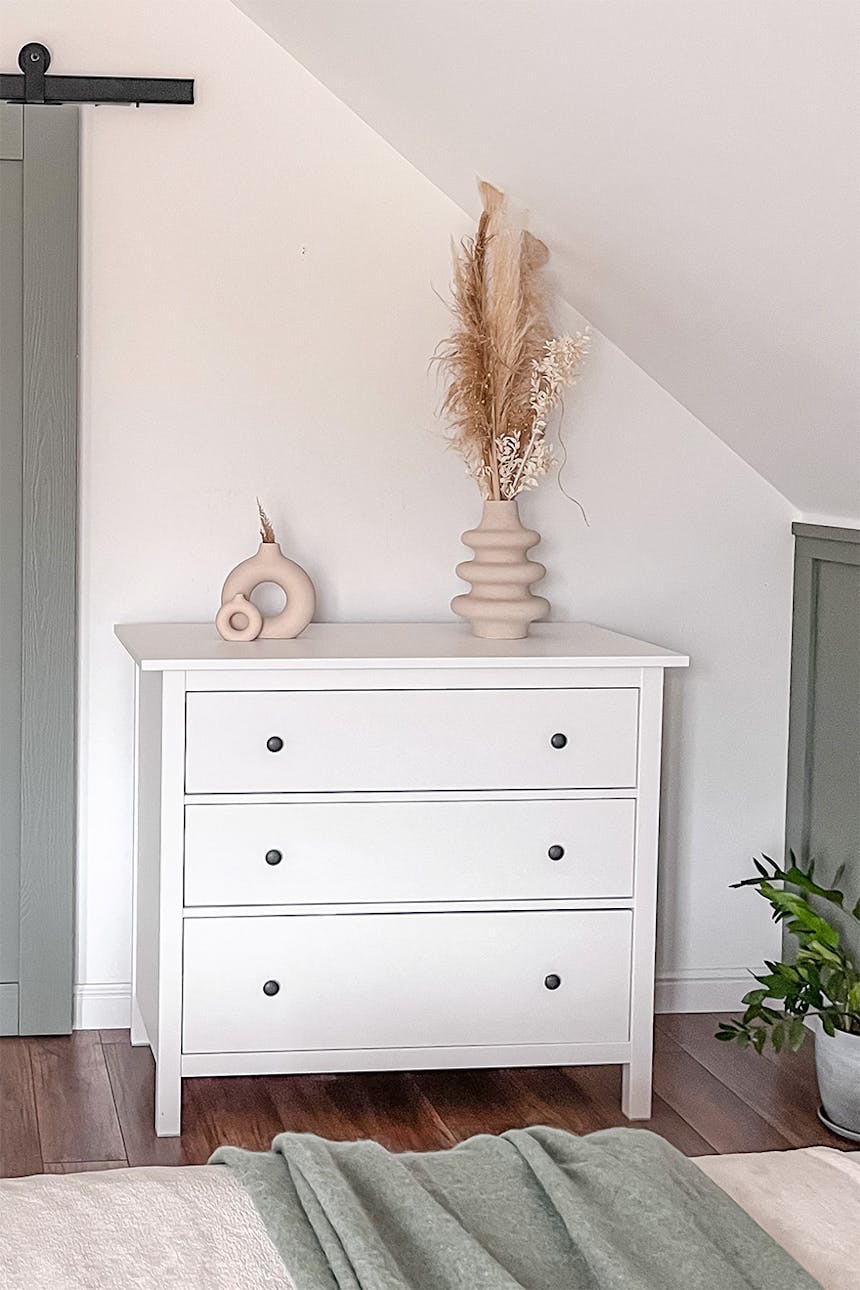 Eine weiße Kommode im skandinavischen Stil steht unter einer schrägen Decke