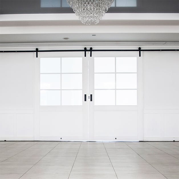 grandes portes coulissantes blanches à deux vantaux avec verre dans l'agencement d'une salle de bal