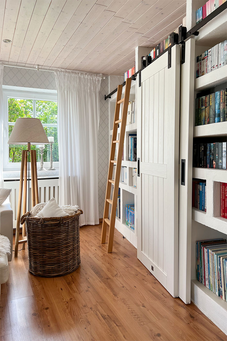 drabinka i białe drzwi przesuwne w aranżacji biblioteki w salonie