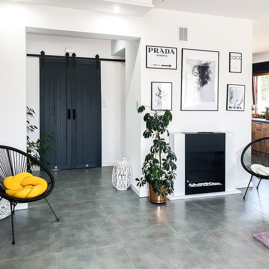 room doors anthracite, anthracite wooden doors, anthracite color doors, double sliding doors, sliding doors in the hall, black accessories in the interior, accessories in anthracite color, photos in a black frame, white and black in a modern home, modern interior, a fireplace in the living room, round openwork armchair