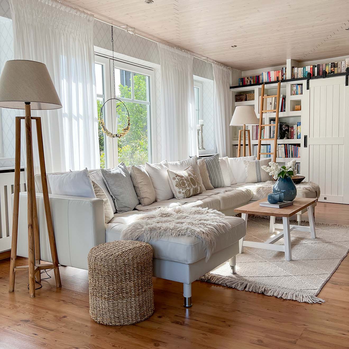 hellgraues Sofa, Holzboden im Wohnzimmer mit Bibliothek