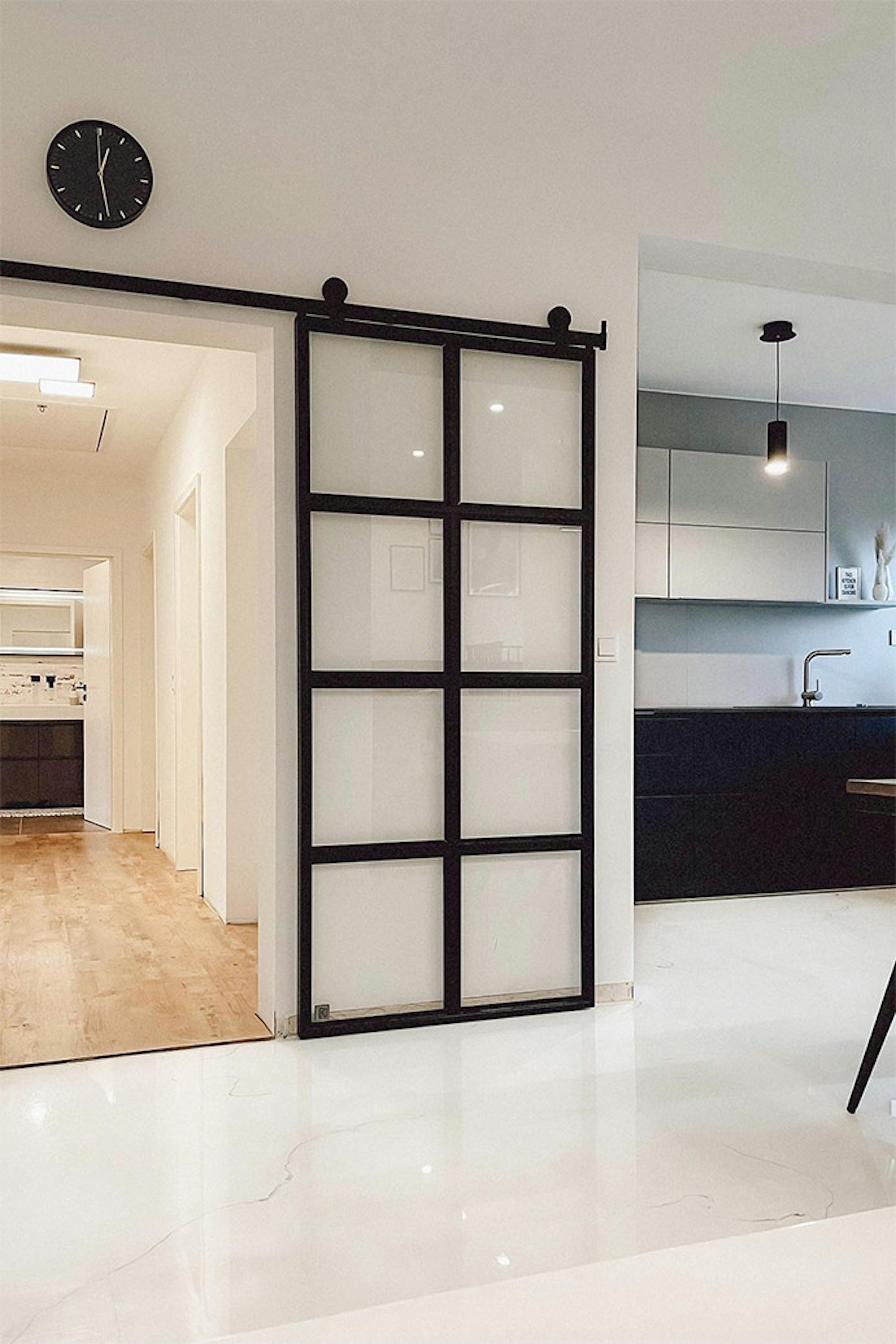 portes coulissantes en verre, porte en métal avec verre transparent, cuisine ouverte en noir et blanc, horloge noire sur mur blanc