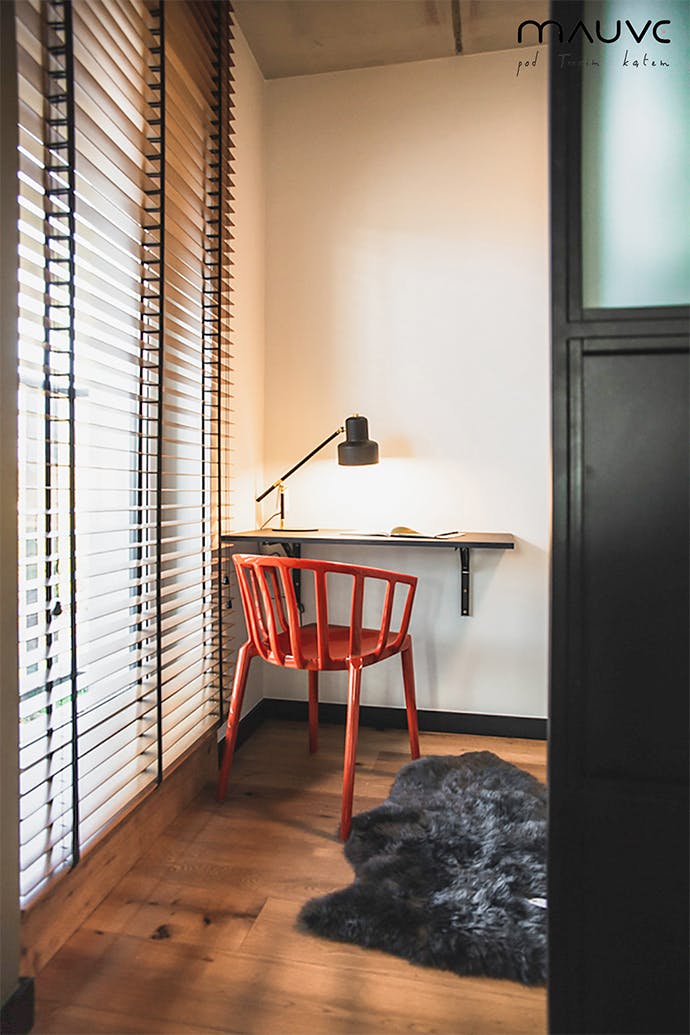 Espace de travail avec petit bureau, lampe en métal et chaise rouge