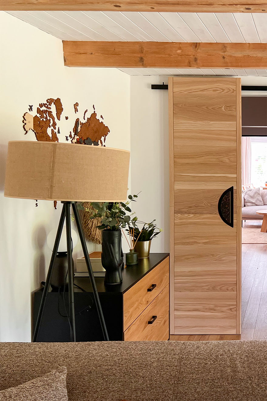 Eine Stehlampe mit Jute Schirm steht neben einer Holzkommode in einem schwarzen Gehäuse