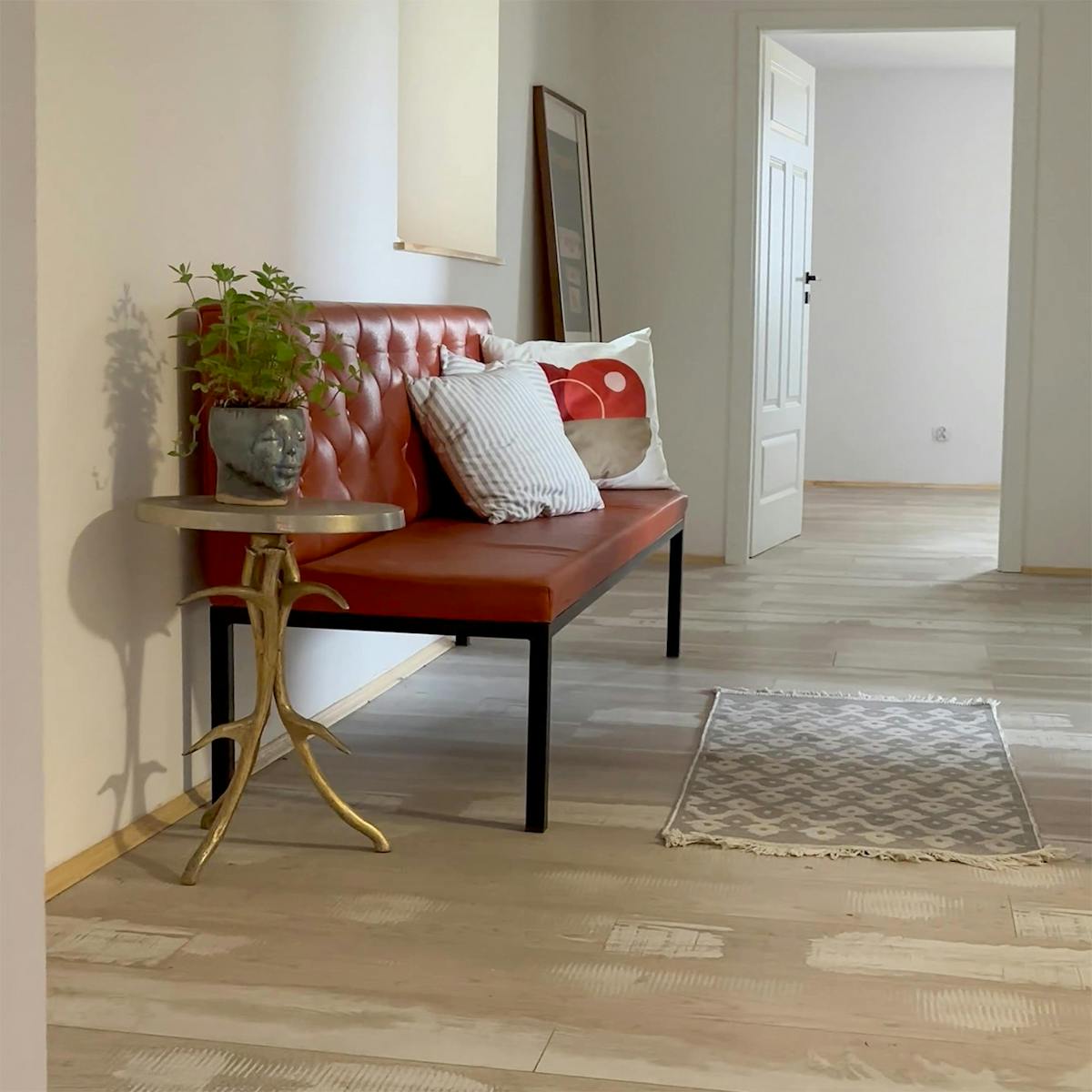 czerwone siedzisko i stolik w przedpokoju domu urządzonego w stylu wiejskim