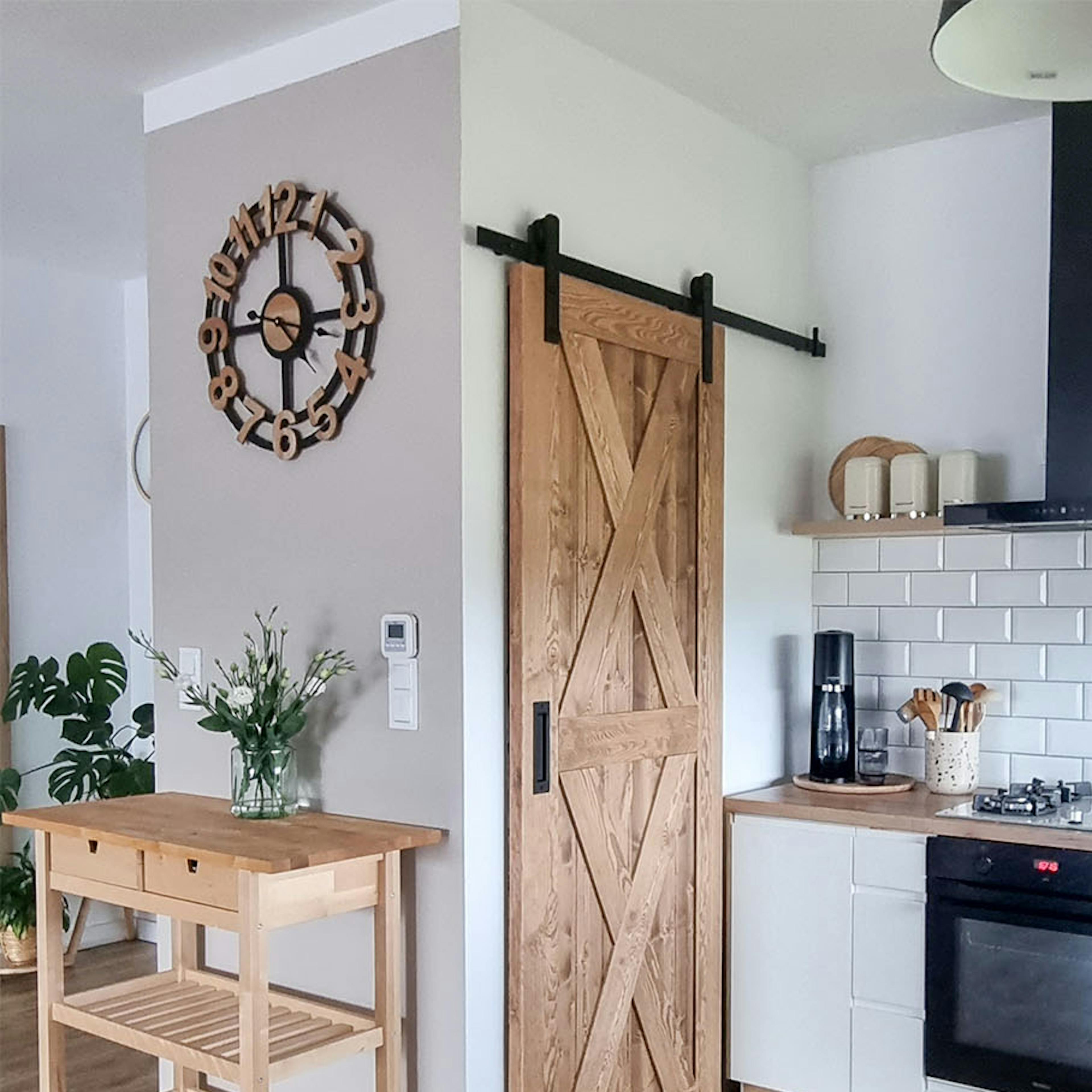 portes coulissantes en bois fermant un garde-manger dans une cuisine décorée dans un style scandinave avec des armoires blanches et des accessoires en bois